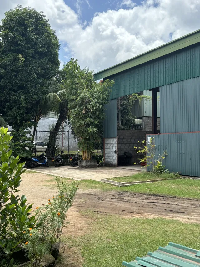 Green factory building with a covered entrance and landscaped grounds